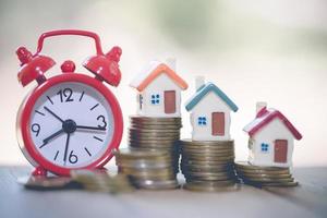 Minature houses resting on coin stacks, concept for property ladder, mortgage and real estate investment photo