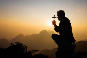 silueta de hombre cristiano rezando a mano, hombre sosteniendo un crucifijo rezando, espiritualidad y religión, mujer rezando a dios. concepto de cristianismo. foto