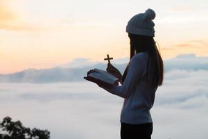 Woman   praying to god with the bible and cross. Woman Pray for god blessing to wishing have a better life. Christian life crisis prayer to god. photo