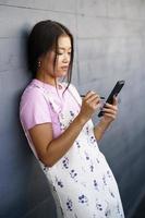 Asian female leaning on wall and using cellphone photo
