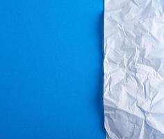 crumpled blank white paper on a blue background photo