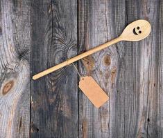 wooden spoon with embedded eyes and a smile, empty brown paper tag is attached to the handle with a rope photo