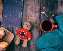 taza de cerámica roja con café negro y muffins horneados foto