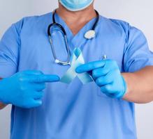 médico con uniforme y guantes de látex con una cinta azul en la mano foto