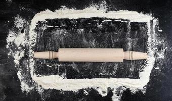 wooden rolling pin on a black background, top view photo