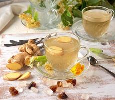 transparent cup of herbal linden tea and pieces of ginger photo