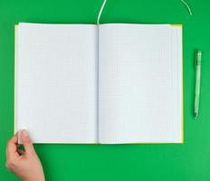 mano femenina sosteniendo un cuaderno abierto en blanco en una celda foto