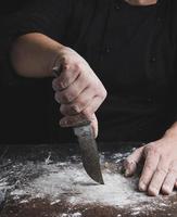 cook in black clothes holding a vintage old knife photo