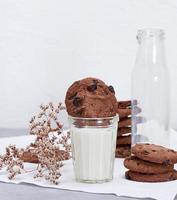 vaso lleno de leche y galletas con chispas de chocolate redondas foto