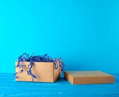 caja de artesanía marrón vacía abierta sobre un fondo de madera azul foto