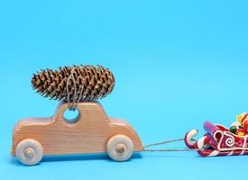 wooden toy car carries on top a pine cone on a blue background photo