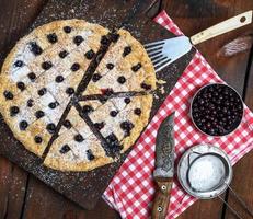 baked round black currant cake cut into pieces photo