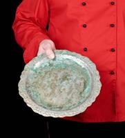 chef in red uniform holds in his hand an empty iron round dish photo