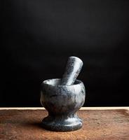 stone mortar with pestle for grinding spices on a brown wooden board, low key photo