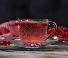 té viburnum caliente en una taza transparente con asa y platillo foto