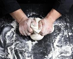 baker kneads white wheat flour dough photo