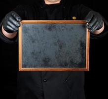 chef in black uniform and black latex gloves holds an empty wooden frame photo