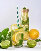 cold drink of fresh lemons, lime, mint green and pieces of ice in a glass photo