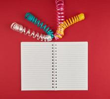 open notebook in line and multicolored serpentine on a red background photo