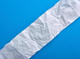 strip of crumpled blank white paper on a blue background photo