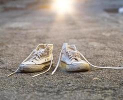 par de zapatillas blancas muy viejas con cordones desatados foto