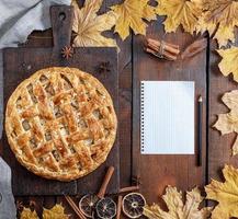 baked whole round apple pie on a brown wooden board photo