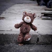 little teddy bear sitting on the side of the road during the day photo