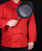 cocinar con uniforme rojo sosteniendo una sartén negra redonda vacía foto