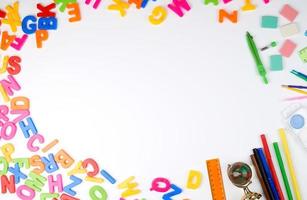 letras del alfabeto inglés multicolores y útiles escolares en un fondo blanco foto