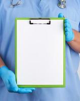 doctor in blue uniform and latex gloves holds a blue holder for sheets of paper photo