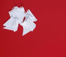 torn to pieces a white sheet of paper on a red background photo