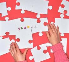 female hand puts white big puzzles on a red background photo