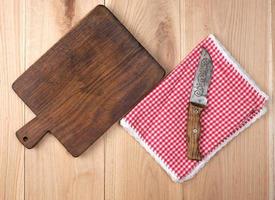 tabla de cortar de cocina de madera vieja vacía y cuchillo en una mesa foto