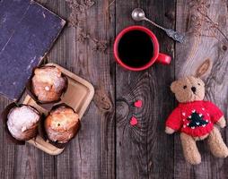 red ceramic mug with black coffee and baked muffins photo