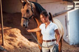 Getting ready for the ride. Horsewoman in white uniform with her horse at farm. Ready for the ride photo
