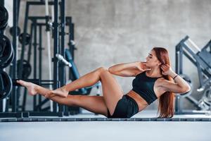 Young fitness girl in black sportive clothes doing yoga exercises in gym photo