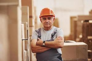 Portrait of senior storage worker in warehouse in uniform and hard hat photo