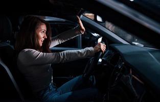 Side view of young woman that inside of brand new modern automobile photo