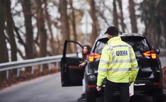 Male police officer in green uniform walking to the vehicle on the road photo