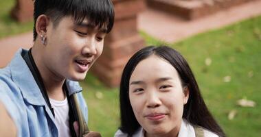 Closeup of Happy young asian blogger couple waving hand via camera and looking at camera in ancient temple. Smiling male and female selfie. Holiday, vacation and Travel concept. video