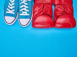 pair of red boxing gloves and blue textile sneakers photo