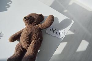 Teddy bear toy lying down on the table. Conception of domestic violence photo