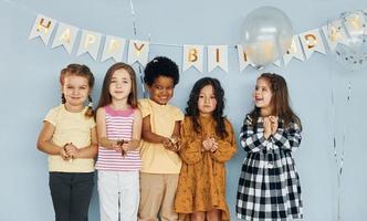 Balloons and confetti. Children on celebrating birthday party indoors have fun together photo