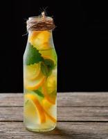 summer refreshing drink lemonade with lemons, mint leaves, lime in a glass bottle photo