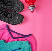 sport textile shoes and other items for fitness on a pink background photo