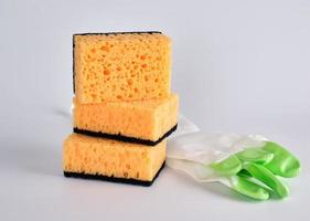 stack of yellow kitchen sponges for washing dishes and gloves photo