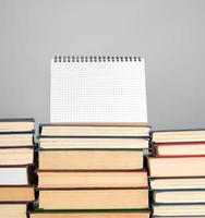 open blank notebook is standing on the stack of books photo