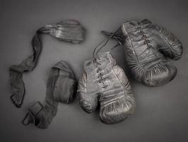 guantes de boxeo negros de cuero vintage muy antiguos con cordones y una venda elástica negra para rebobinar foto