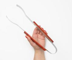 female hand holds tongs with wooden handle against white background, photo