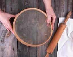 female hands holding a round wooden sieve for flour photo